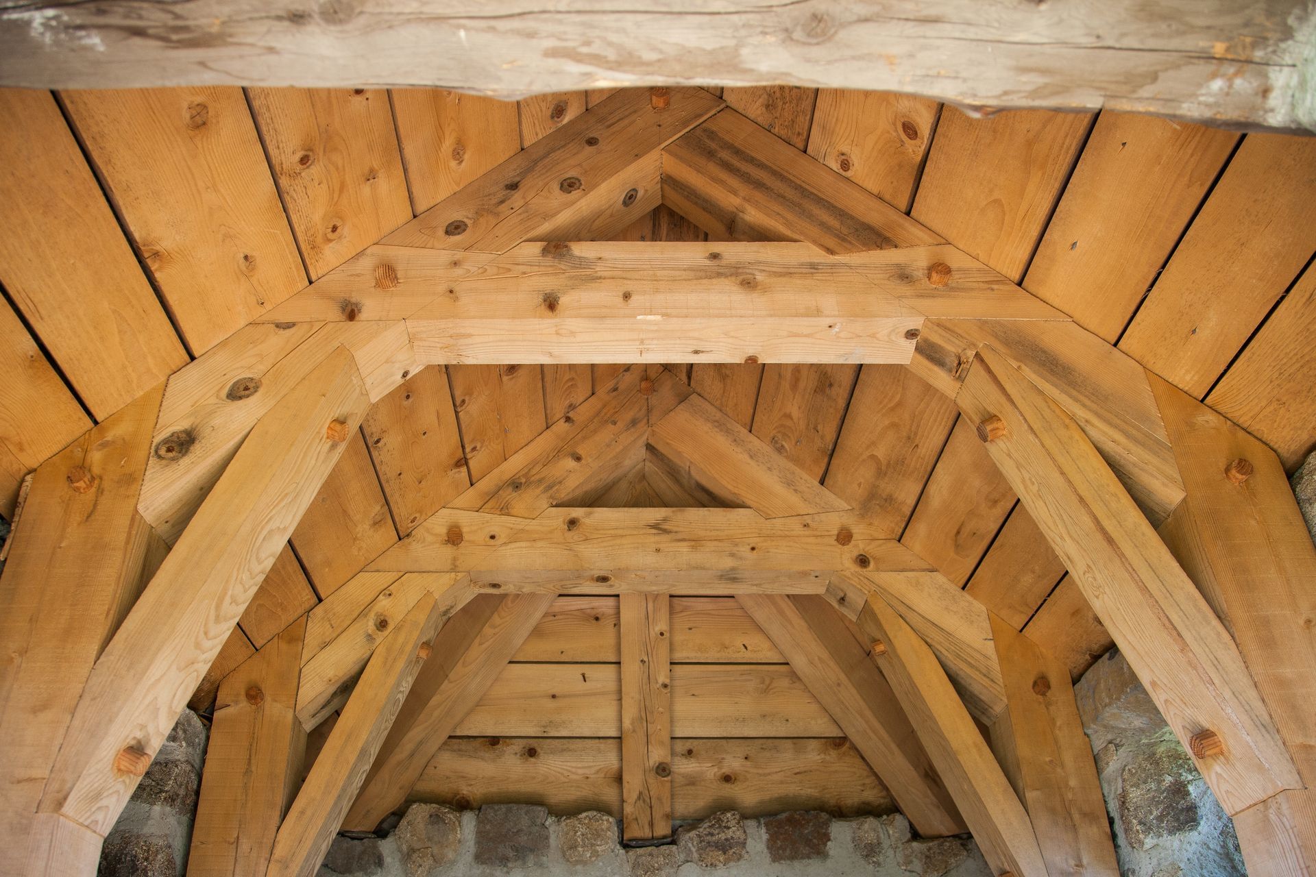 Des poutres et des planches en bois forment un plafond voûté dans un vieux bâtiment.