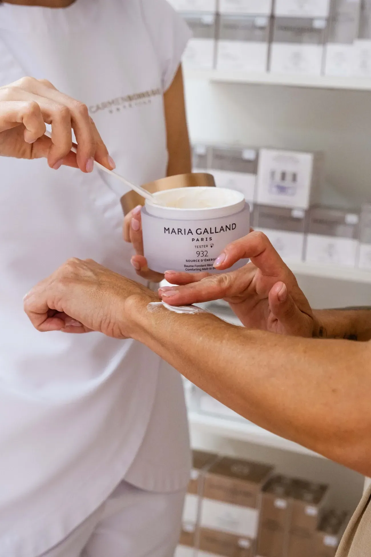 Una mujer está aplicando crema en la muñeca de otra mujer.