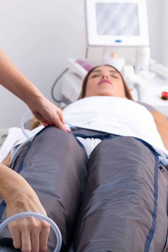Una mujer está acostada en una cama recibiendo un tratamiento en sus piernas.