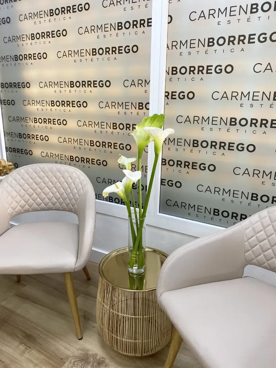 Un jarrón de flores está sobre una mesa delante de dos sillas.