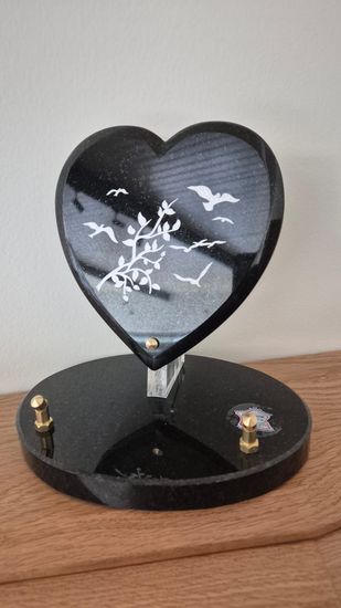 Présentoir décoratif en forme de cœur avec des oiseaux blancs sur un socle noir, posé sur une étagère en bois