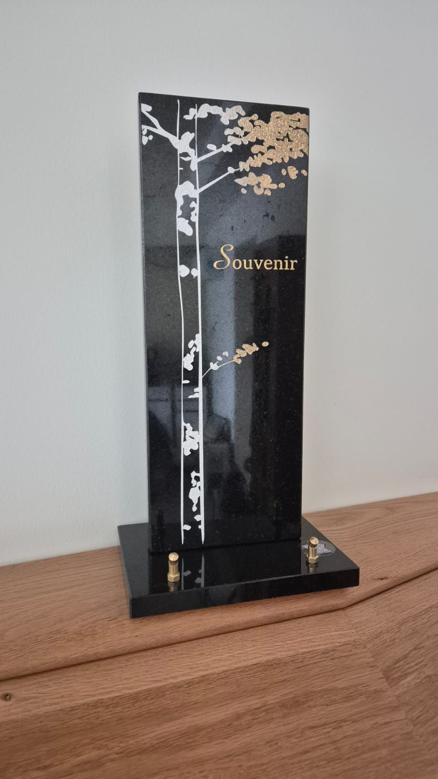 Plaque du souvenir en verre noir avec motif d'arbre blanc et lettrage doré sur une surface en bois
