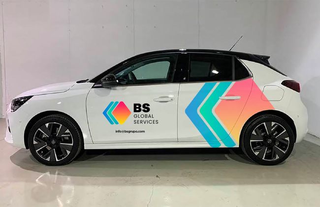 Un coche blanco con una franja de color en el lateral está aparcado en un garaje.