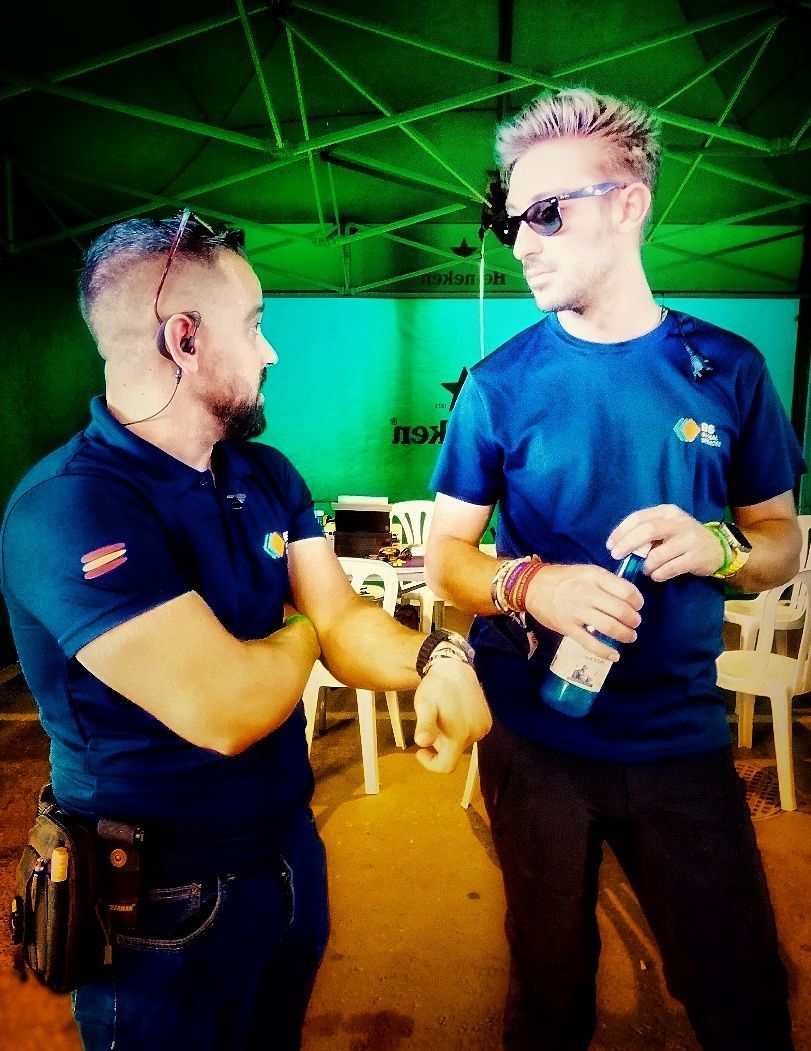 Dos hombres están parados uno al lado del otro y uno tiene una botella de agua en la mano.