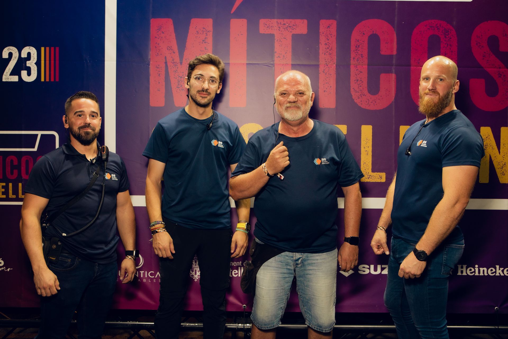 Un grupo de hombres de pie frente a un cartel que dice míticos