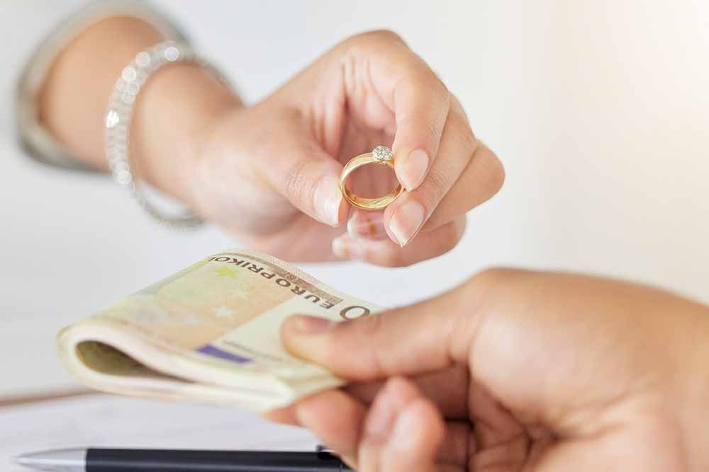 Eine Frau hält einen Ehering vor einem Stapel Geld .