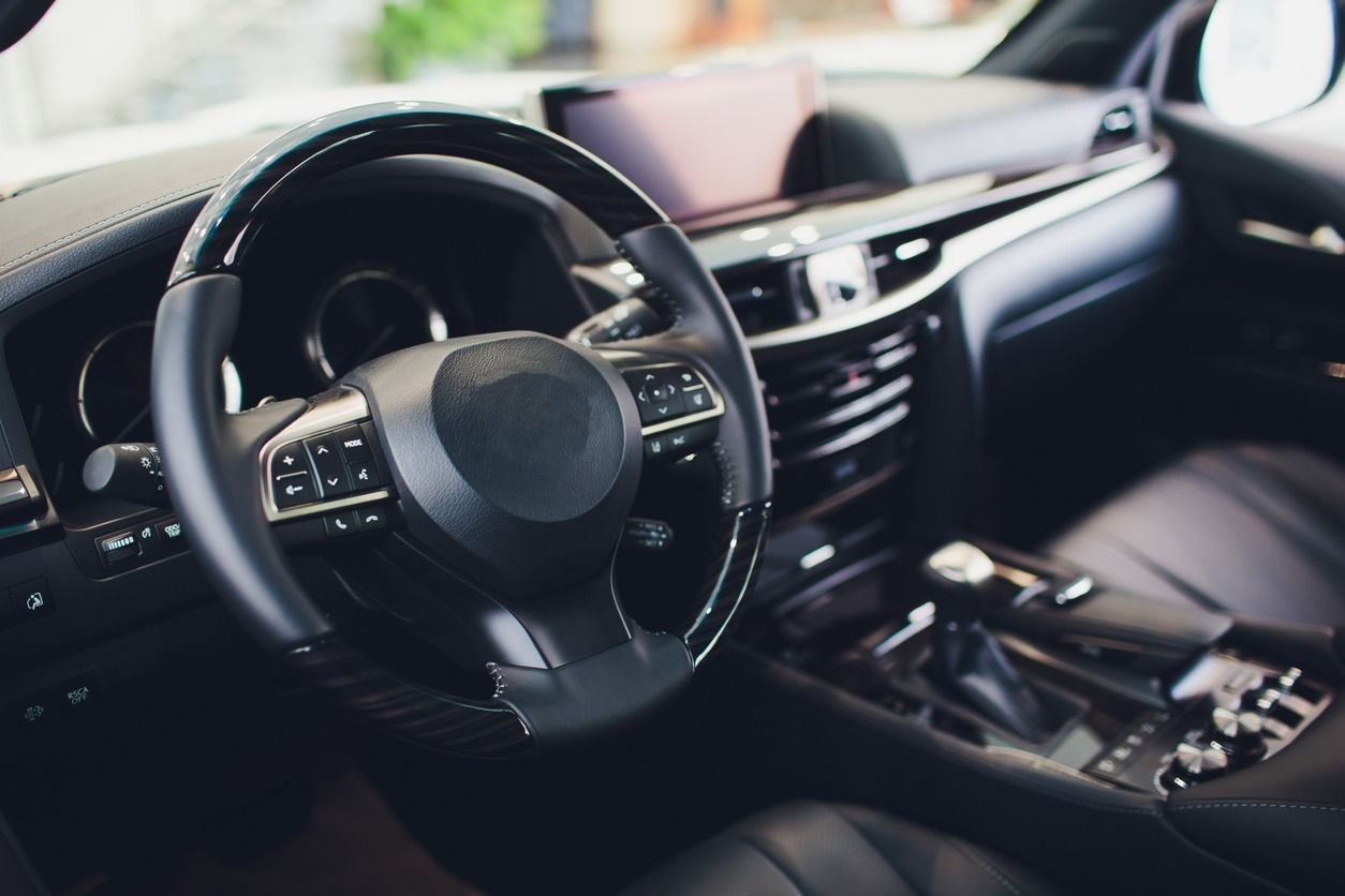 Interior de cuero negro de un coche de lujo: volante, tablero y palanca de cambios visibles.