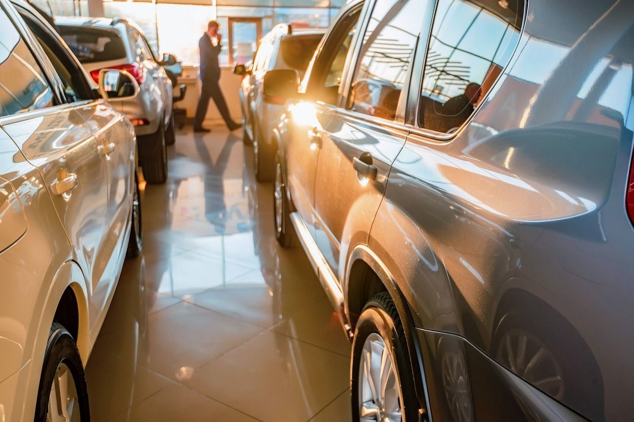 Autos expuestos en una sala de exposición bien iluminada. Al fondo, una persona camina entre los vehículos.