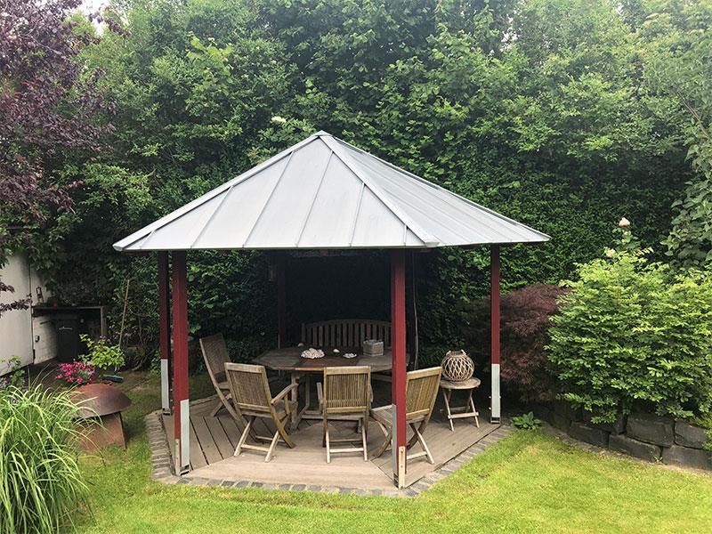 Ein Pavillon mit Tisch und Stühlen in einem Garten
