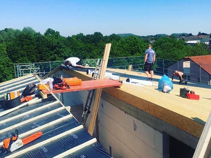 Eine Gruppe Männer arbeitet auf dem Dach eines Gebäudes.