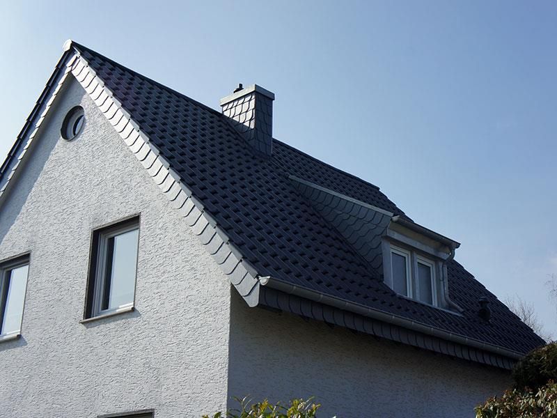 Ein weißes Haus mit einem schwarzen Dach und einem Schornstein