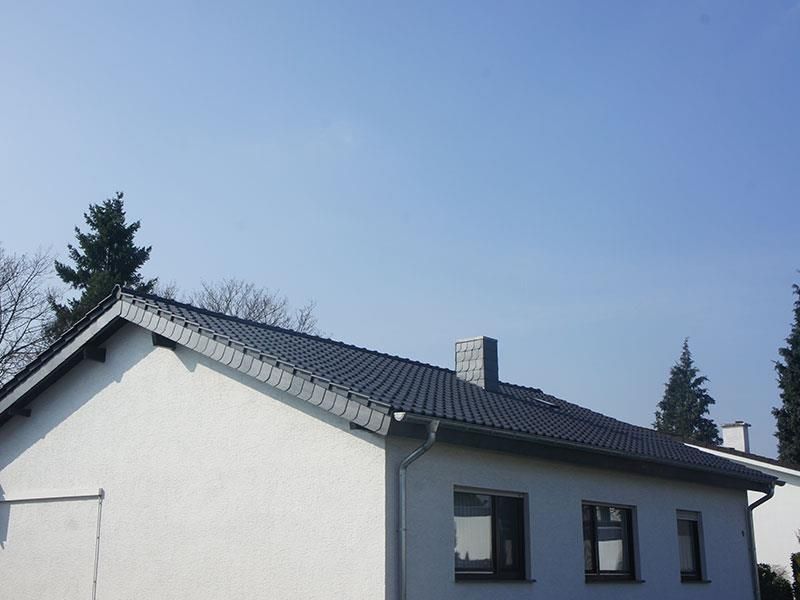 Ein weißes Haus mit einem schwarzen Dach und einem Schornstein