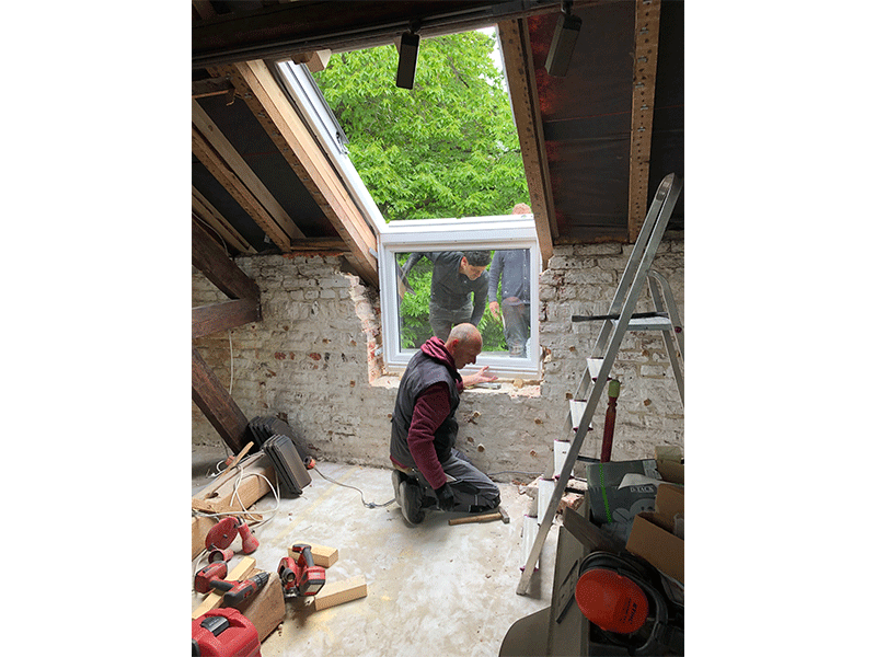 Ein Mann arbeitet an einem Fenster auf einem Dachboden.