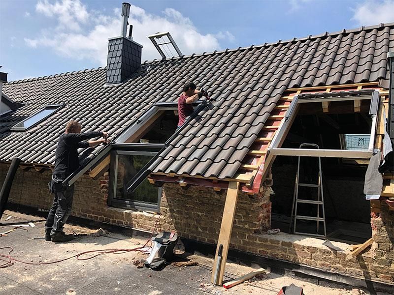 Zwei Männer arbeiten auf dem Dach eines Hauses.