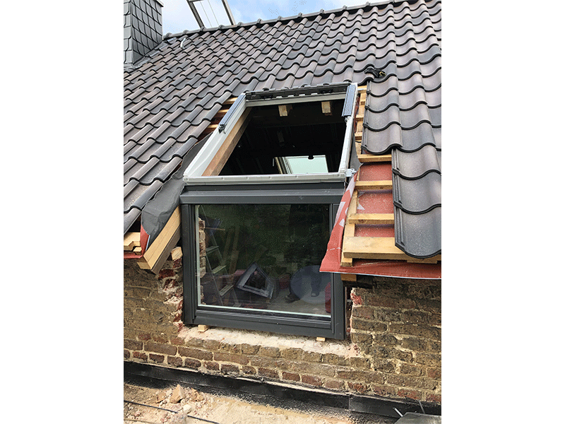 Auf dem Dach eines Gebäudes wird ein Fenster eingebaut.