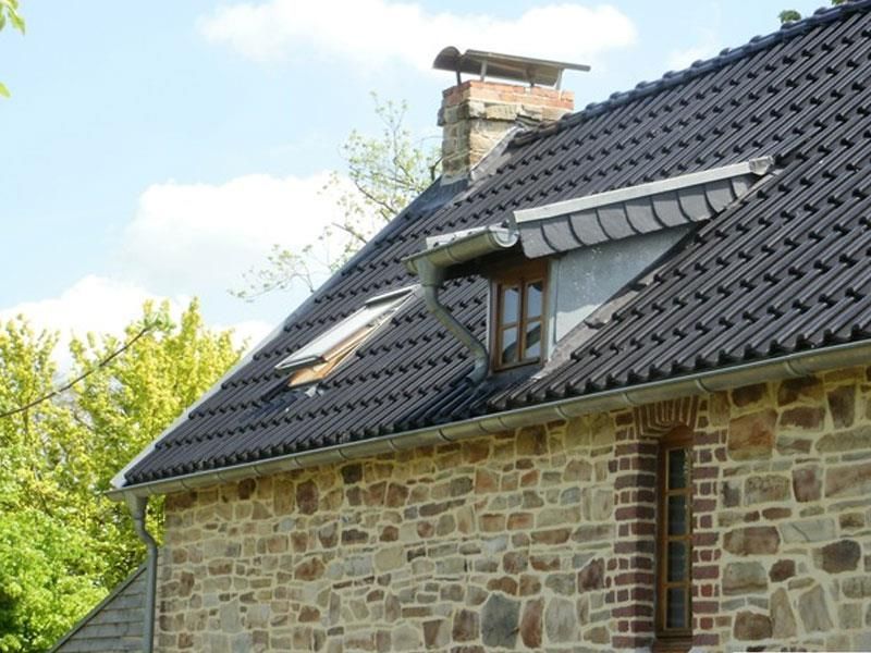 Ein Steingebäude mit einem schwarzen Dach und einem Fenster