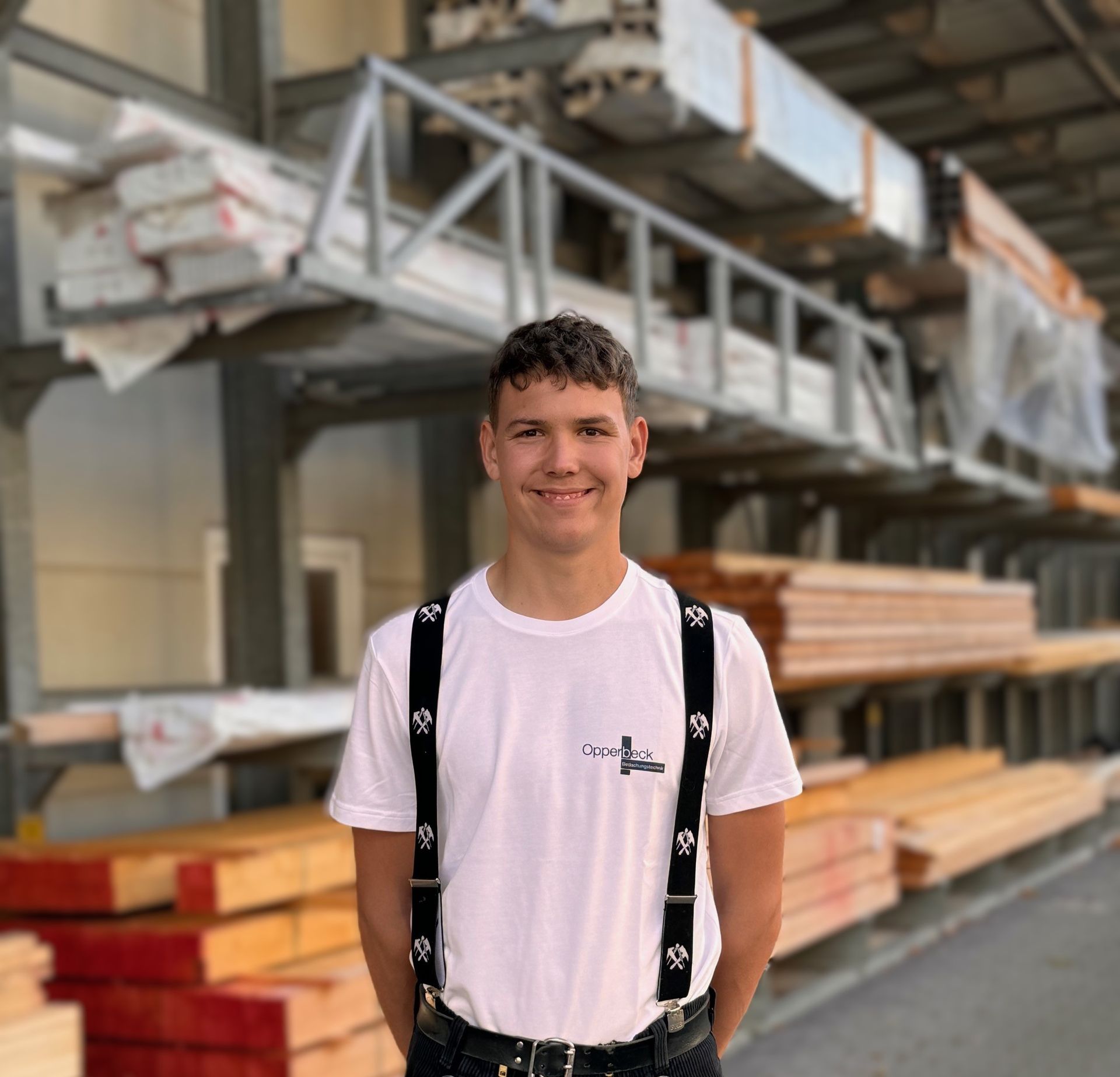 Ein junger Mann mit Hosenträgern und einem weißen Hemd mit dem Buchstaben L darauf