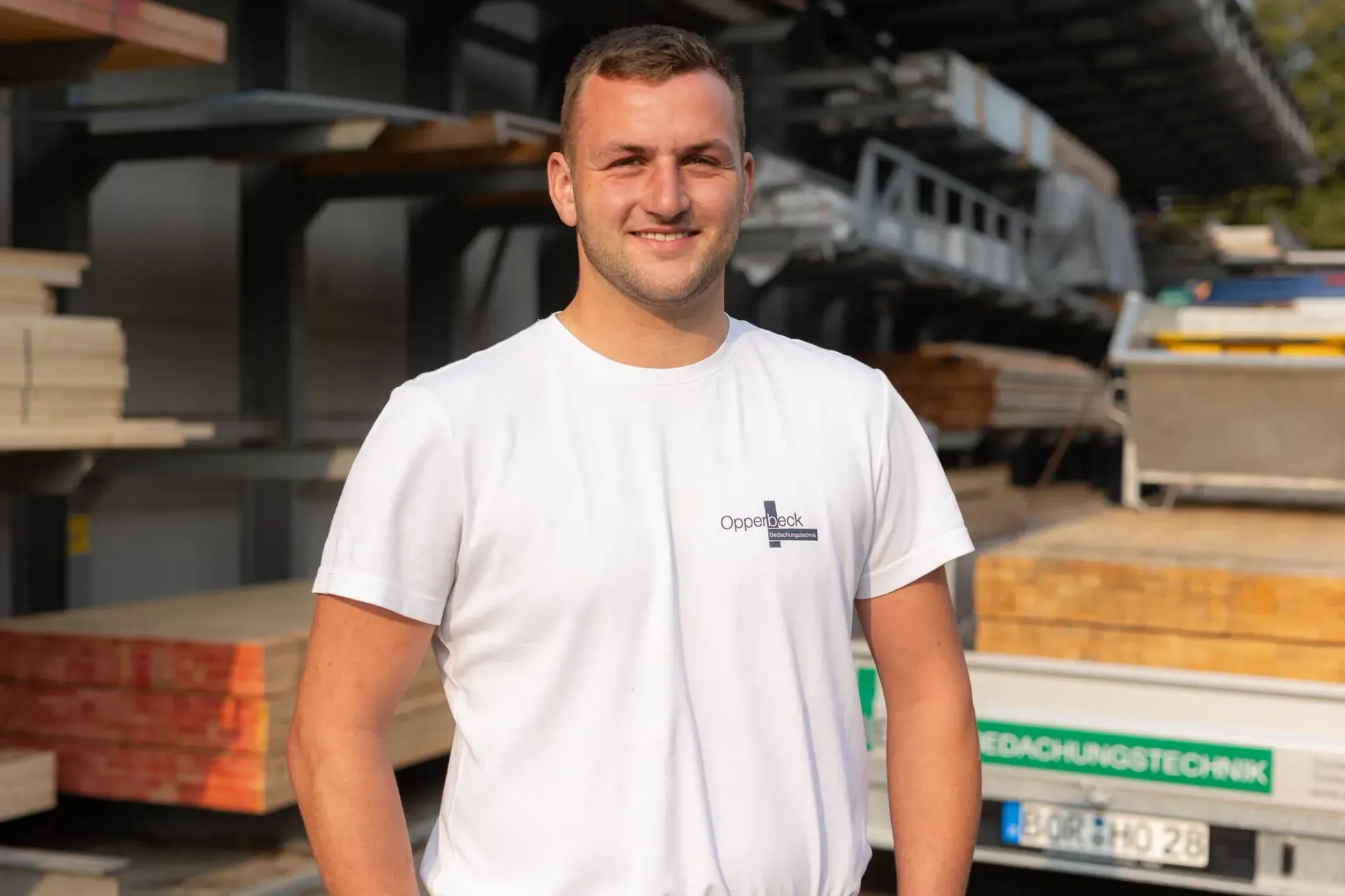 Ein Mann im weißen Hemd steht vor einer Lagerhalle.