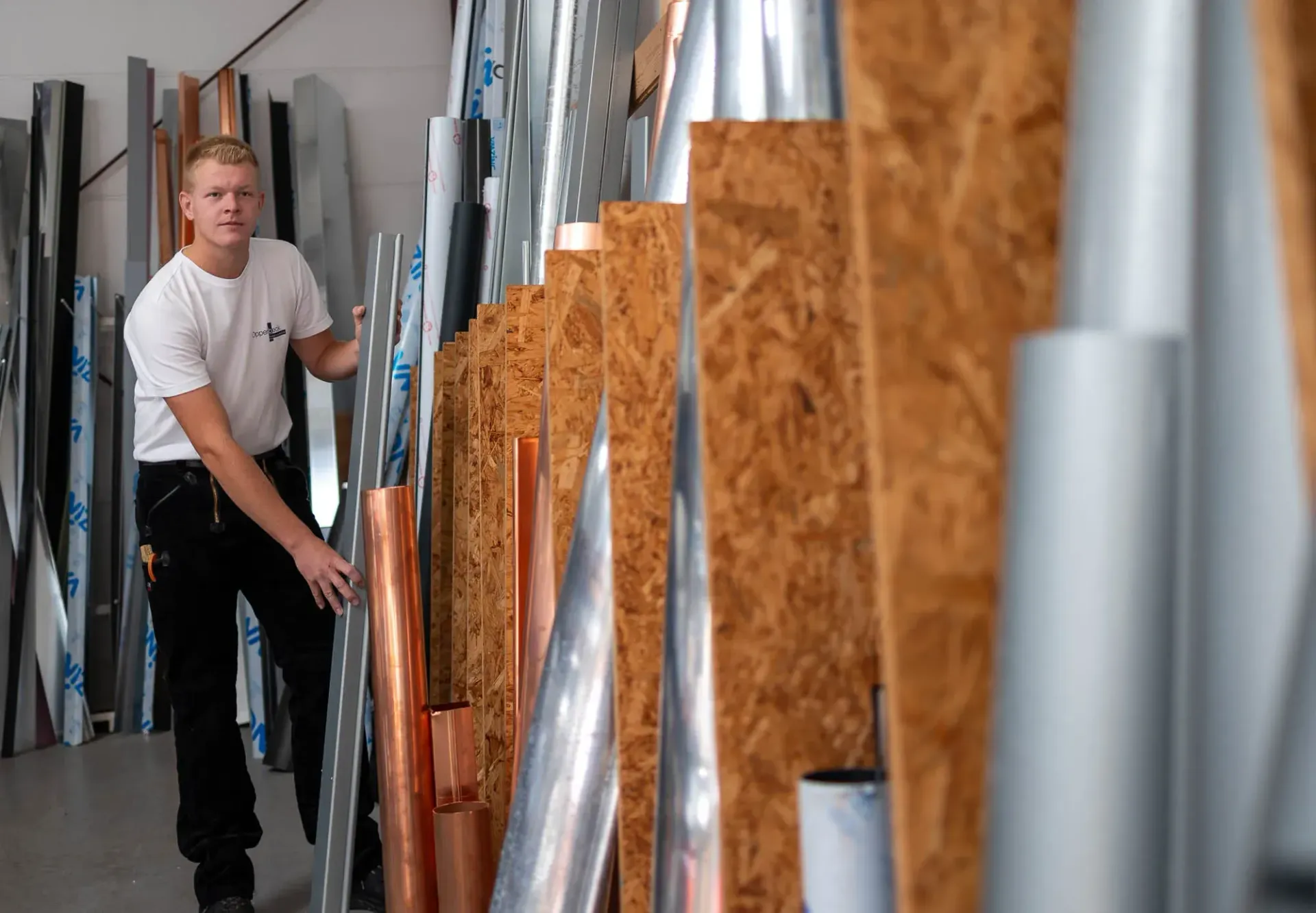 Ein Mann steht in einer Lagerhalle, umgeben von Rohren.