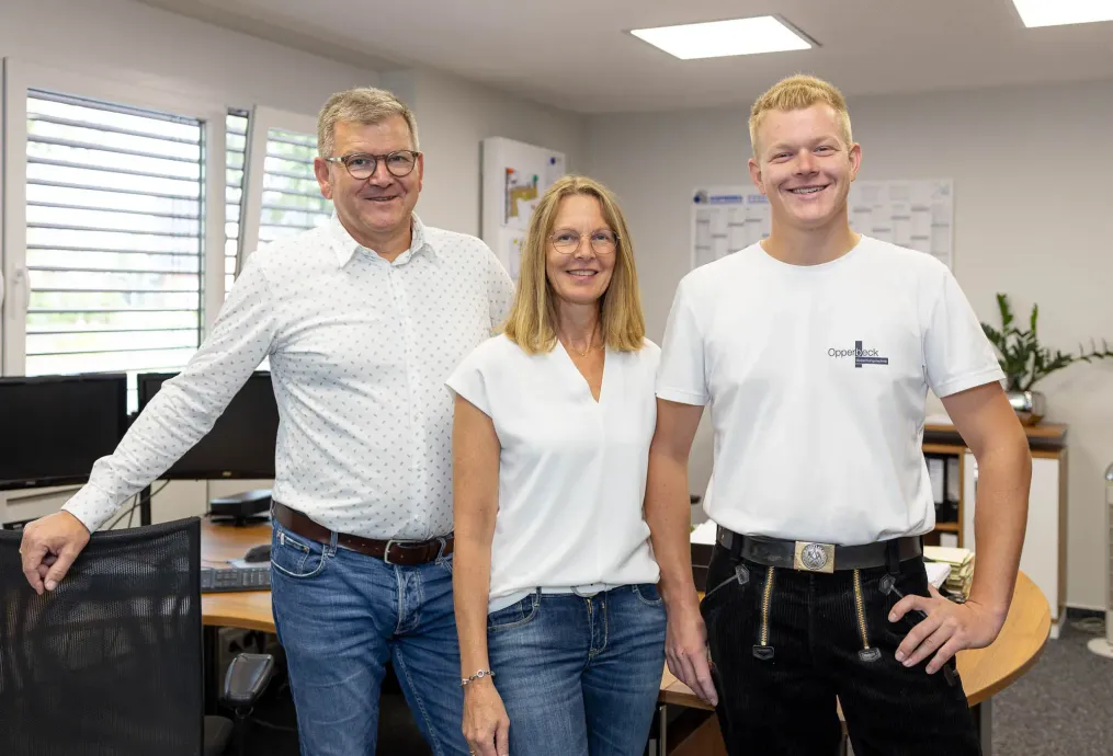 Ein Mann, eine Frau und ein Junge posieren in einem Büro für ein Foto.