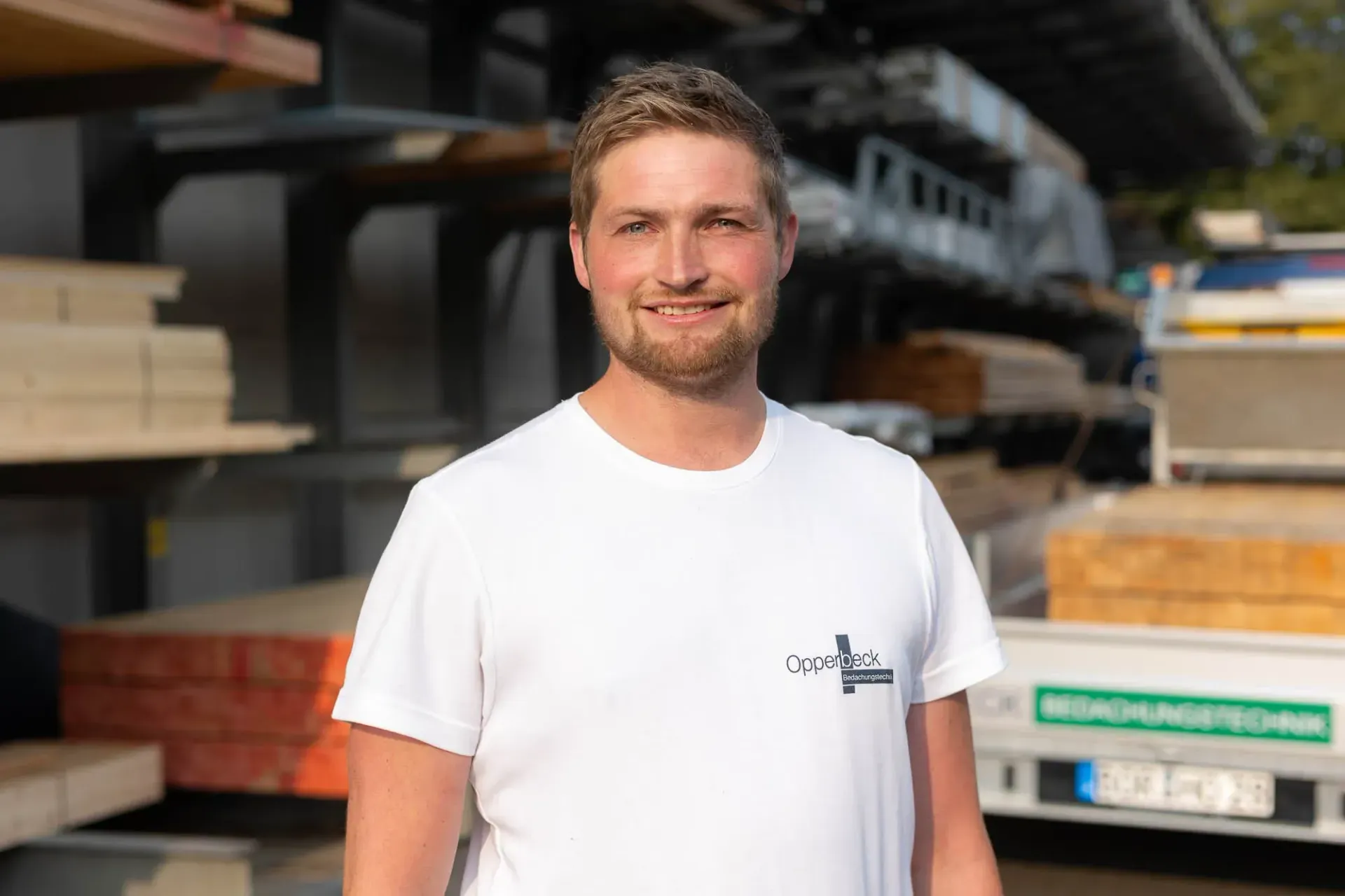 Ein Mann in einem weißen T-Shirt steht vor einem Lastwagen.