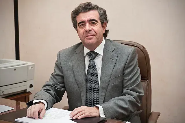 Un hombre con traje y corbata está sentado en un escritorio.