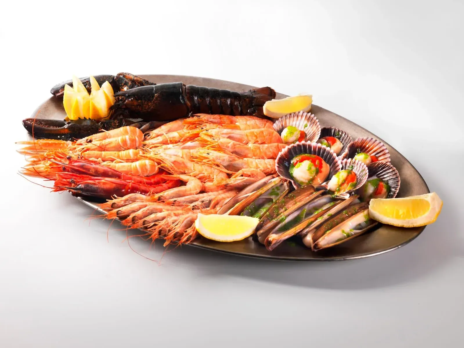 Plato de mariscos con langosta, camarones, mariscos y rodajas de limón en una bandeja negra.