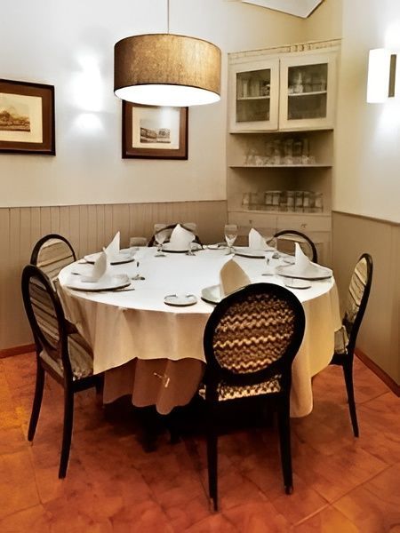 Elegante comedor con mesa redonda, sillas negras e iluminación cálida.
