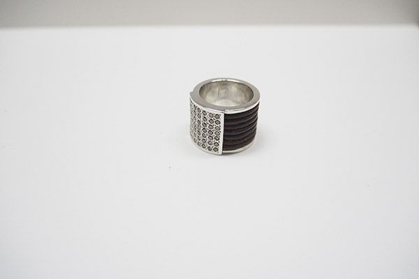 Un anillo de plata con una banda negra reposa sobre una superficie blanca.