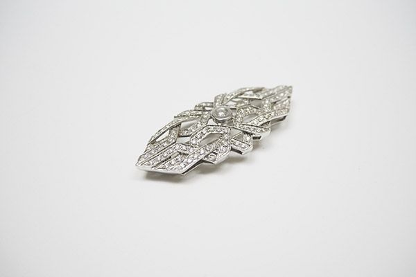Un primer plano de un broche con diamantes sobre una superficie blanca.