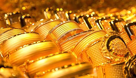 Un primer plano de una pila de pulseras y anillos de oro.