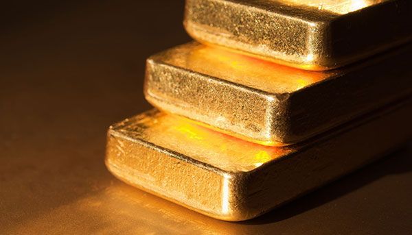 Tres lingotes de oro están apilados uno encima del otro sobre una mesa.