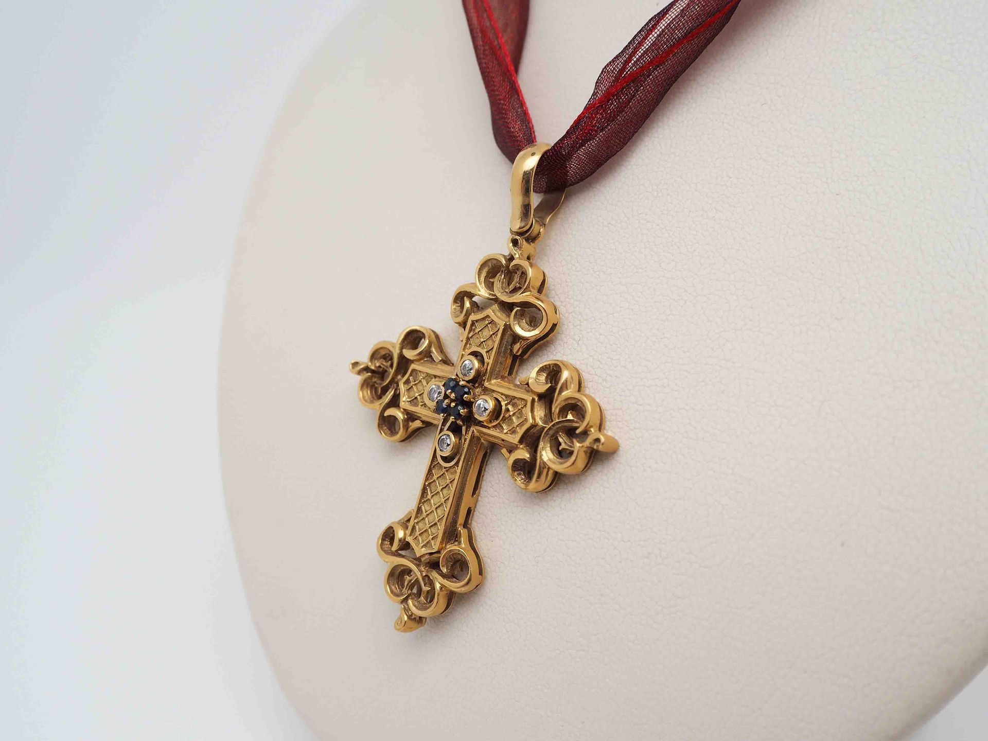 Un collar de cruz de oro con una cinta roja