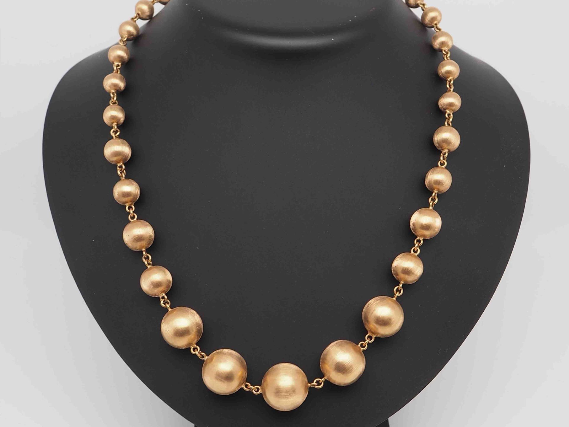 Un collar con cuentas de oro en un maniquí negro.