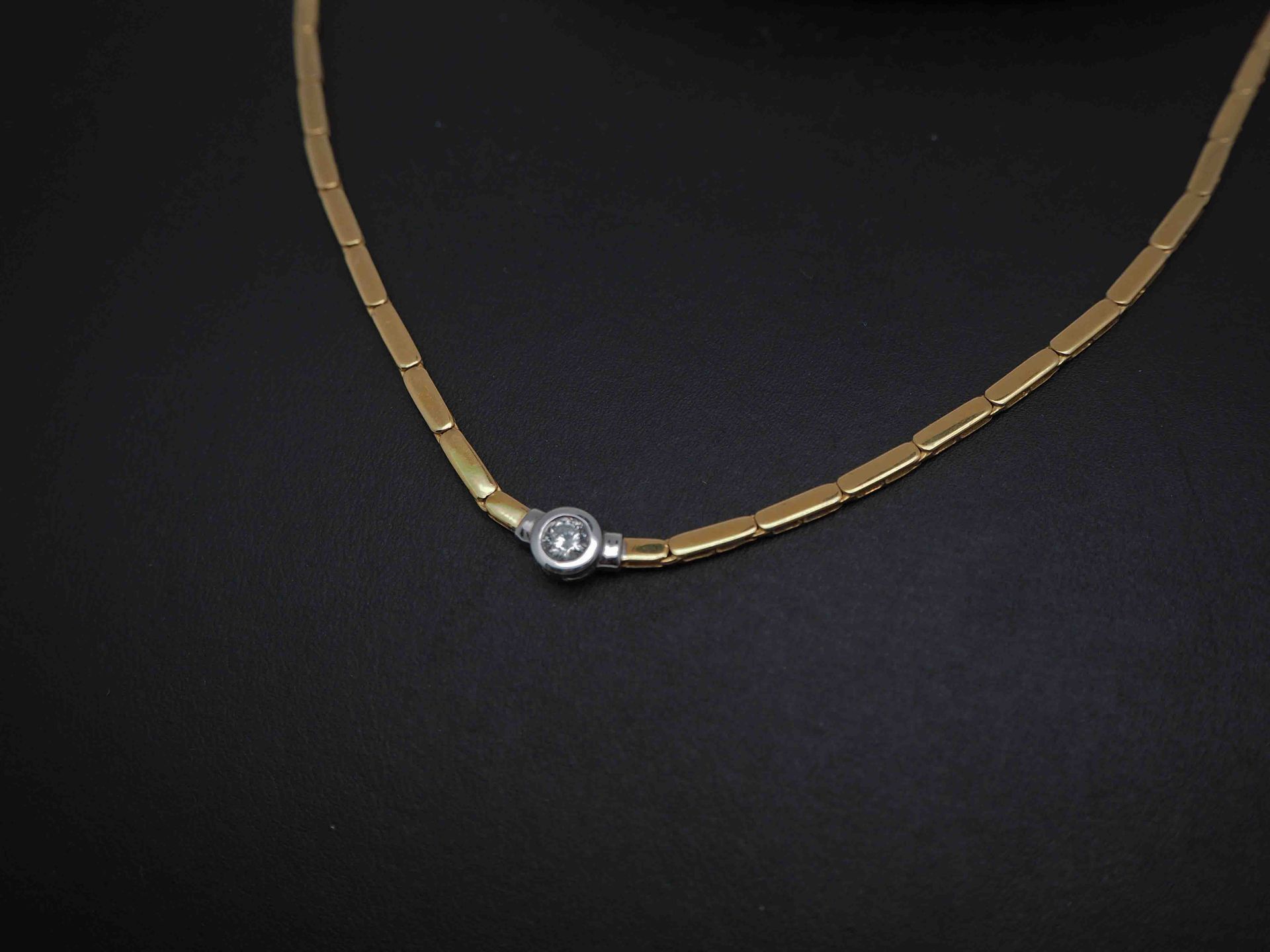 Un collar de oro con un colgante de diamantes sobre un fondo negro.