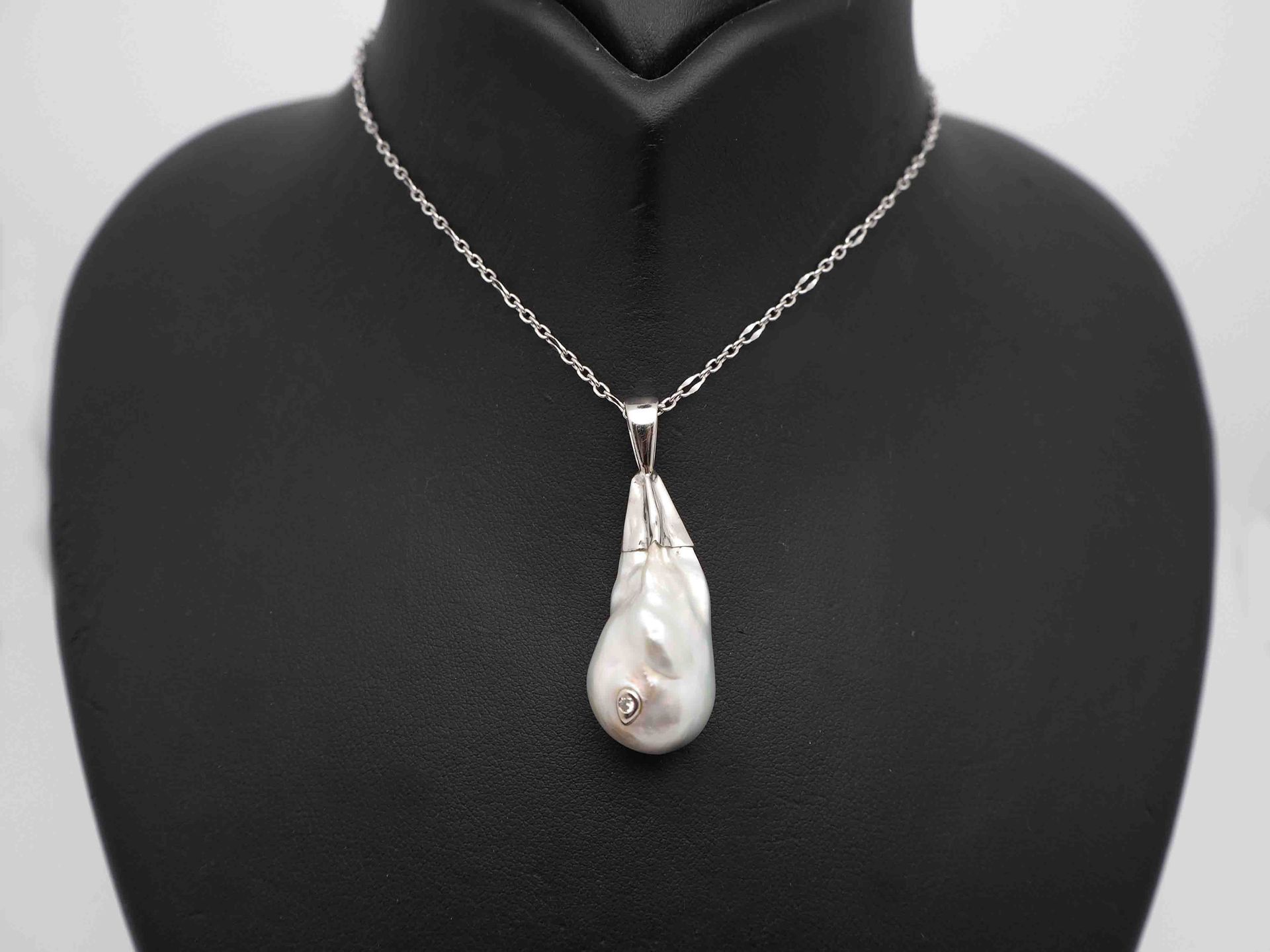 Un collar con un gran colgante de perla está en un maniquí.