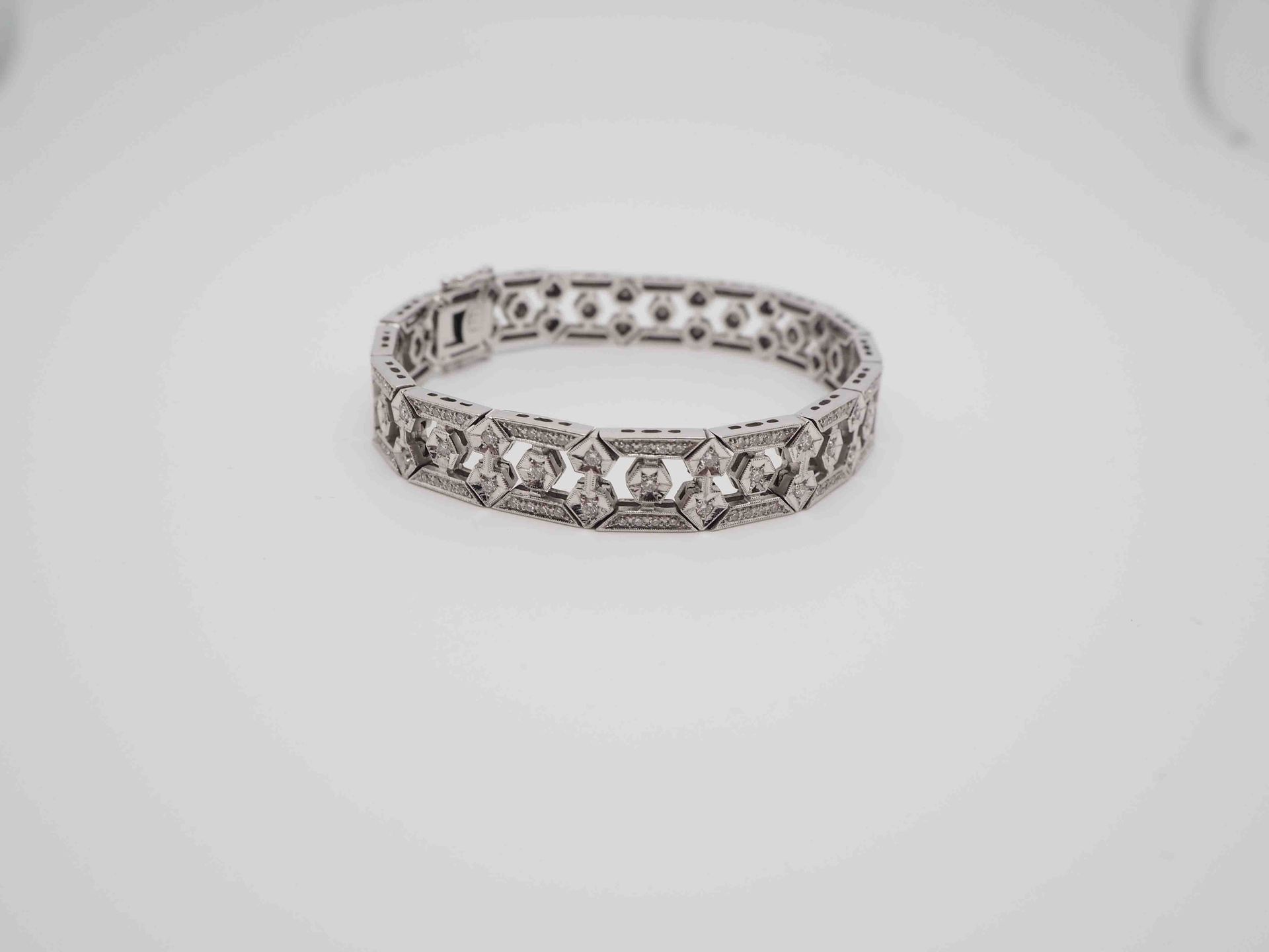 Una pulsera de plata reposa sobre una superficie blanca.