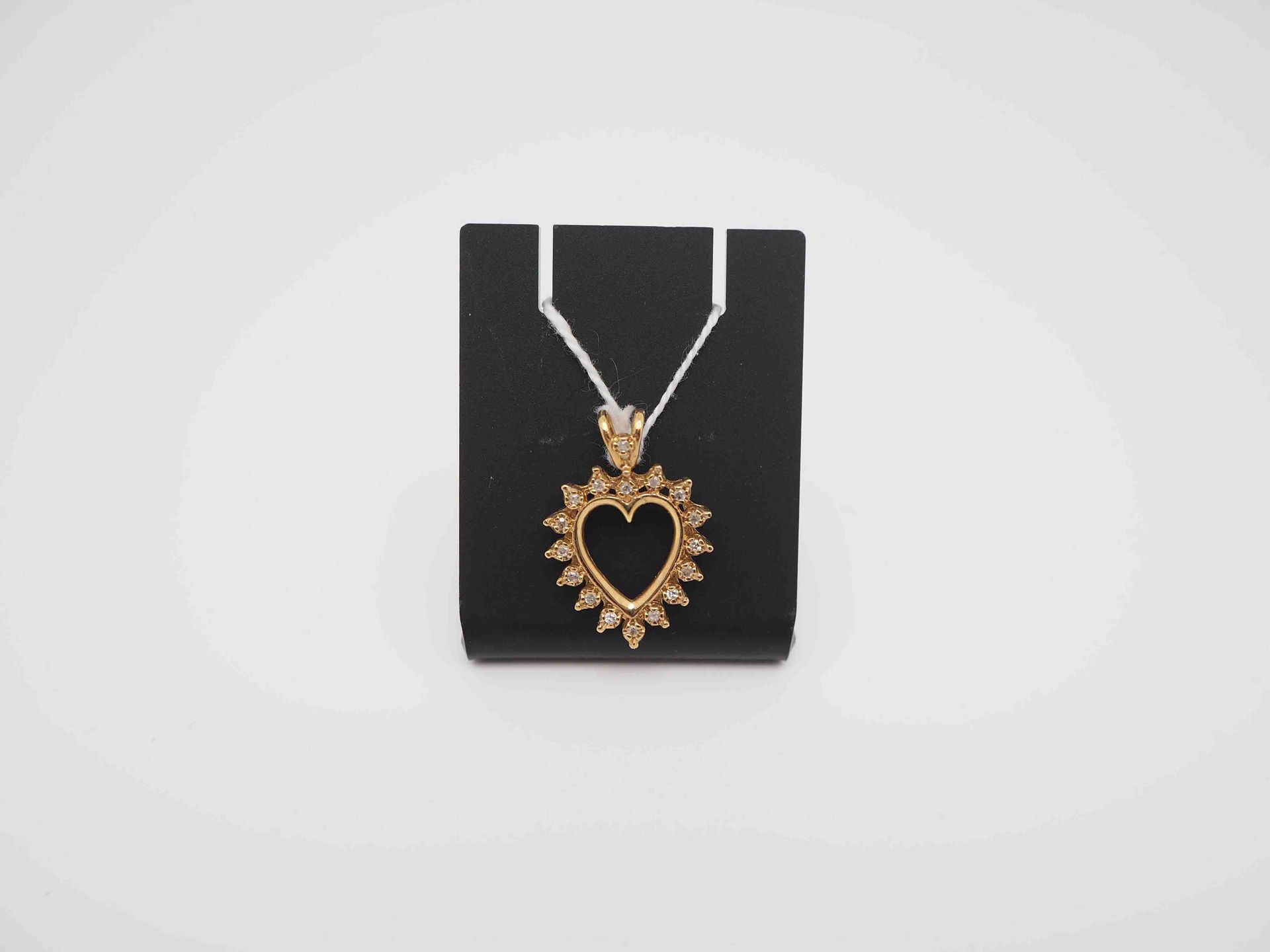Un collar con un colgante en forma de corazón está en una vitrina negra.