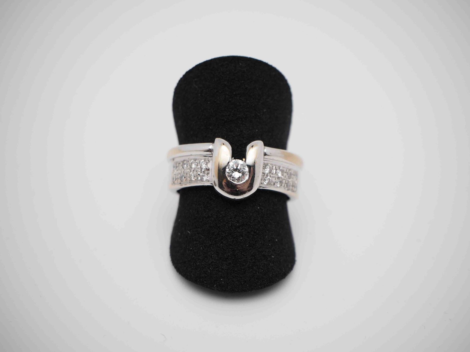 Un anillo de plata está sobre un soporte de anillo negro.