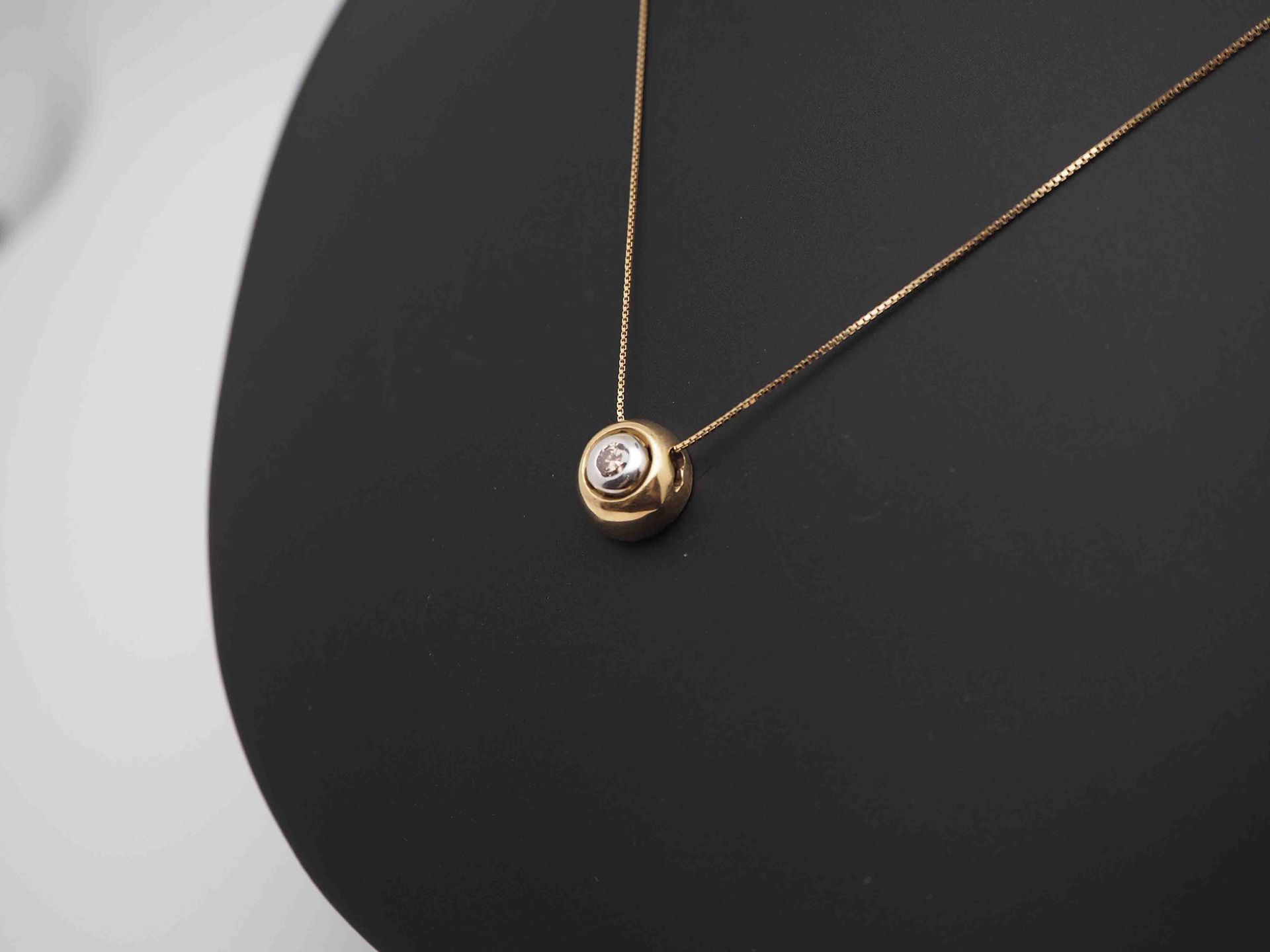 Un collar de oro con un colgante de diamantes en un maniquí negro.
