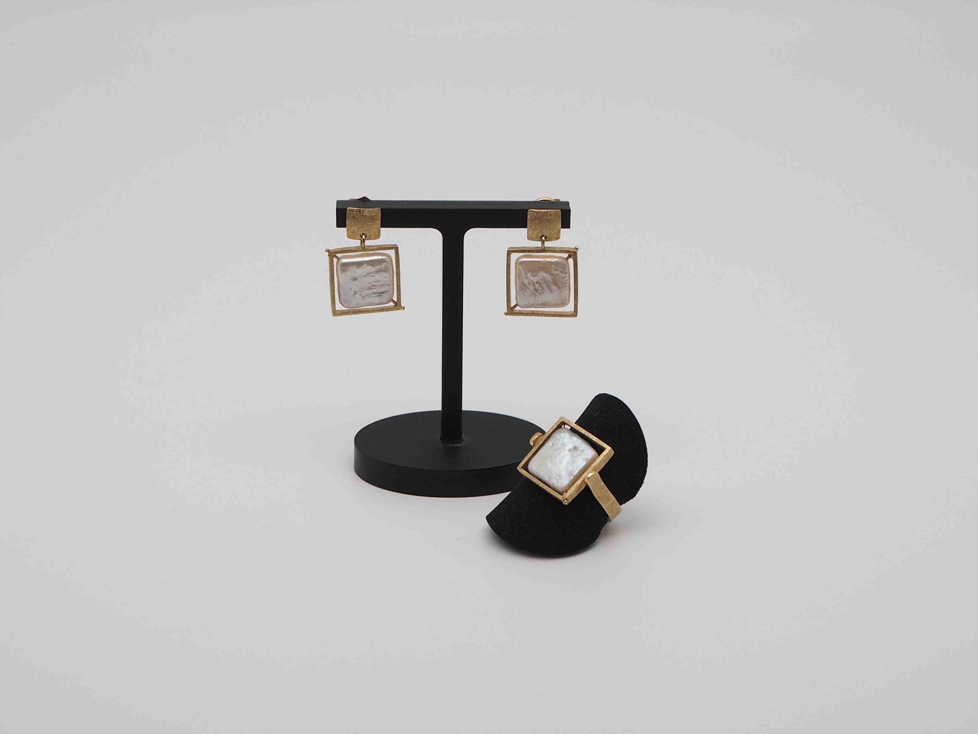 Un par de pendientes y un anillo están expuestos en un soporte.