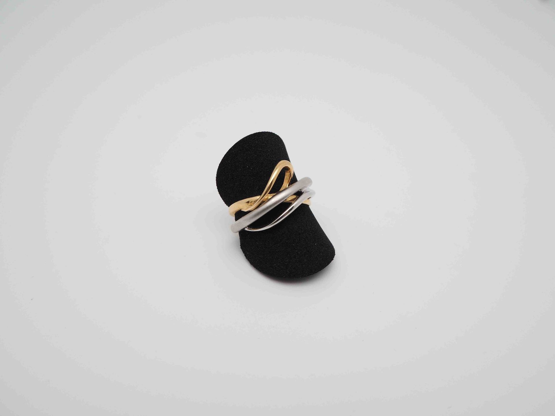 Un anillo está colocado encima de un soporte de anillo negro sobre una superficie blanca.