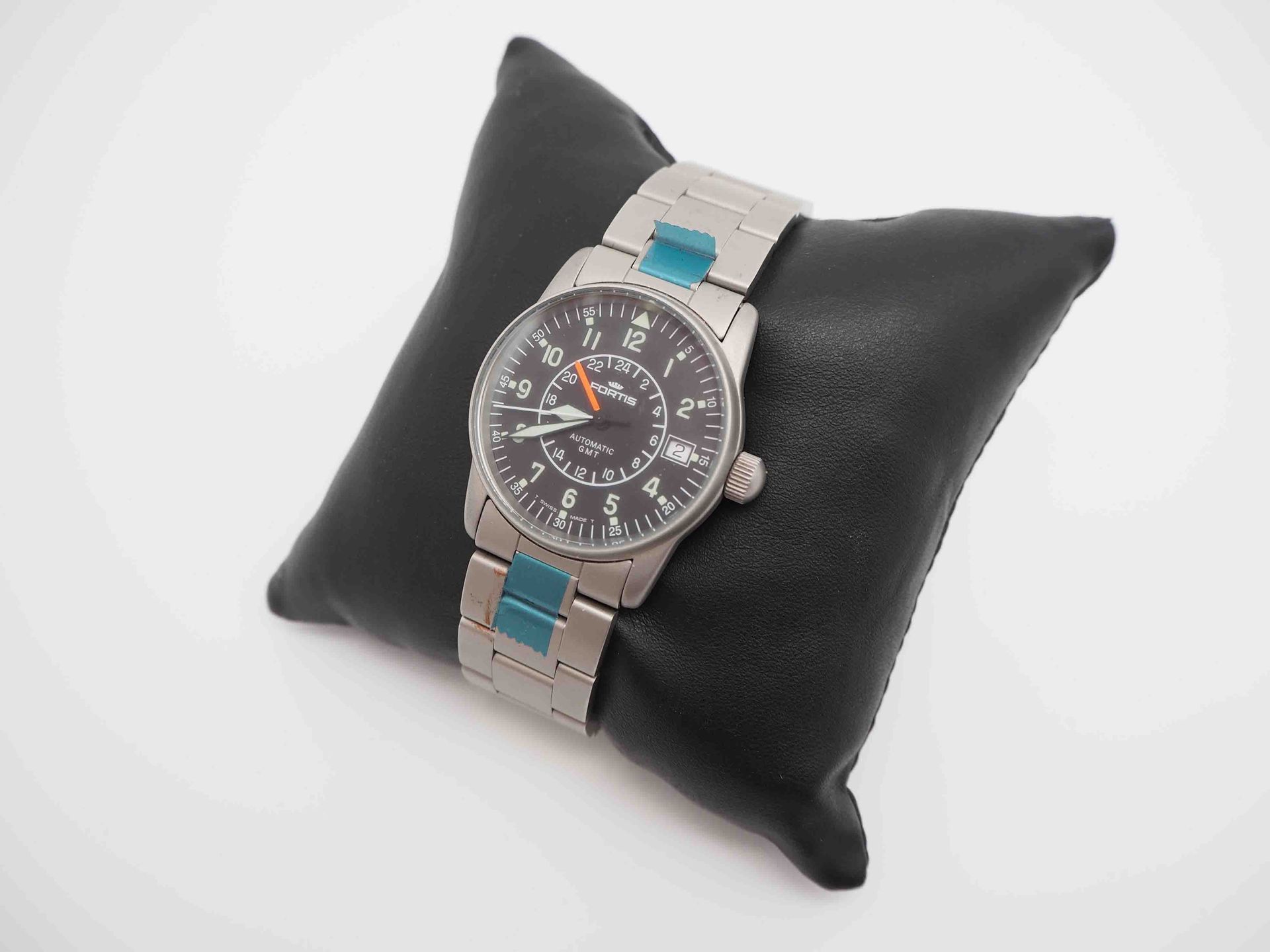 Un reloj de plata reposa sobre una almohada negra.