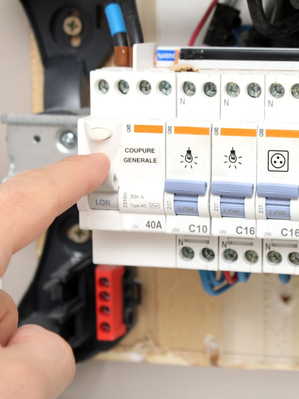 Un doigt appuie sur l'interrupteur principal d'un tableau de distribution électrique.