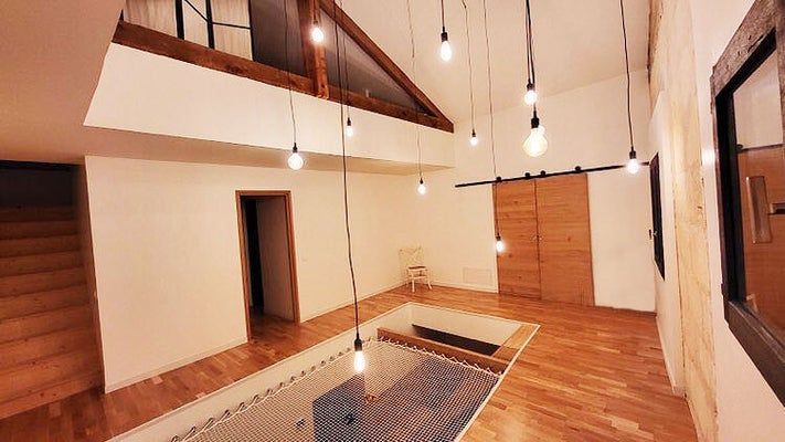 Vue intérieure d'un loft moderne avec parquet, guirlandes lumineuses et espace détente en filet.