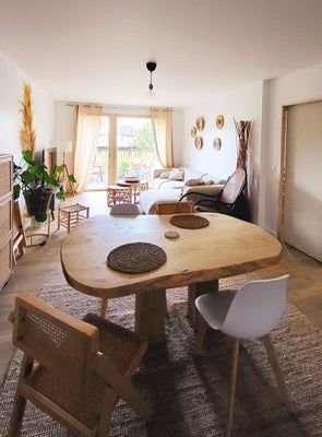 Salon avec table en bois, canapé et décoration aux tons clairs.