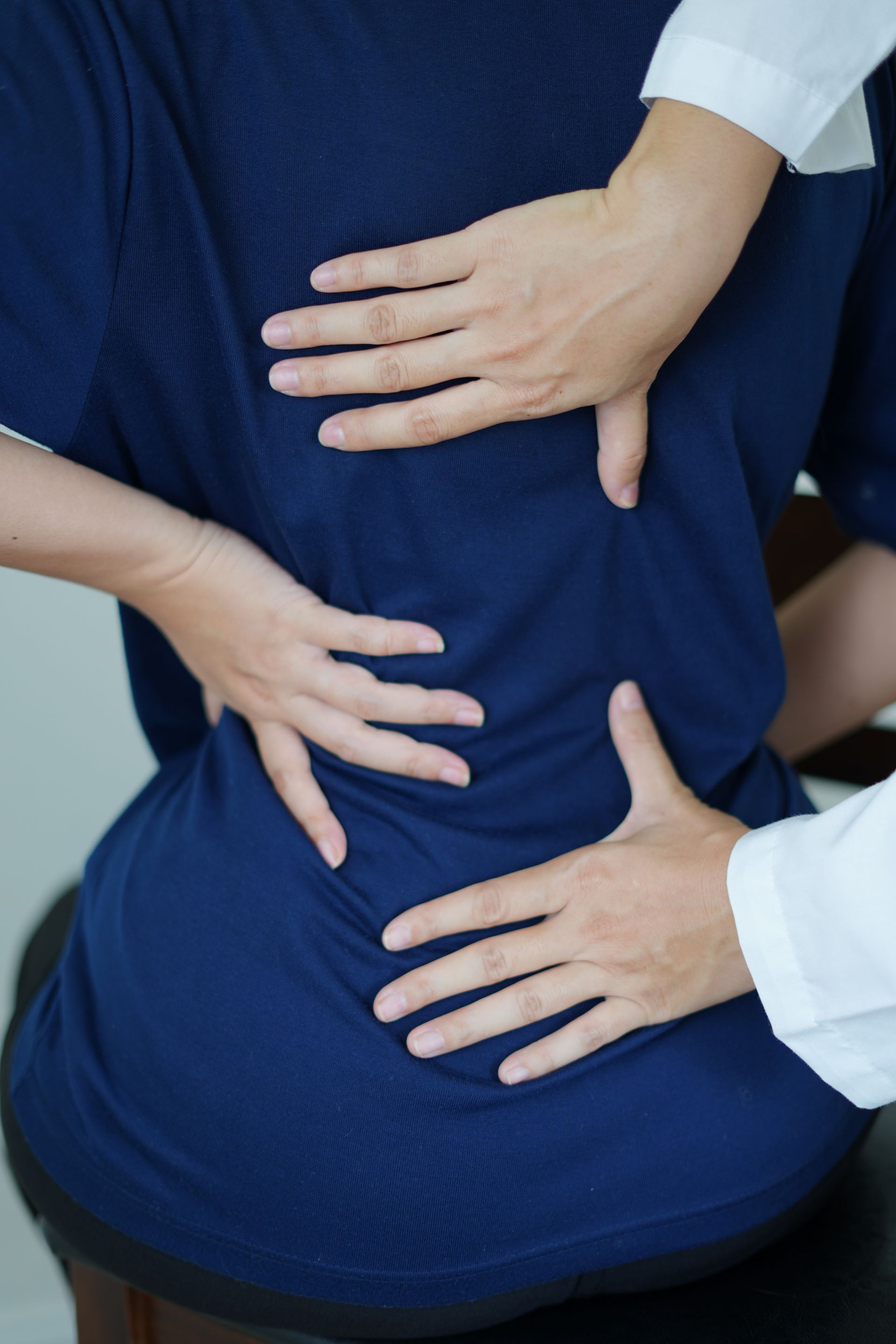 Les mains de l'ostéopathe sur le dos d'une patiente