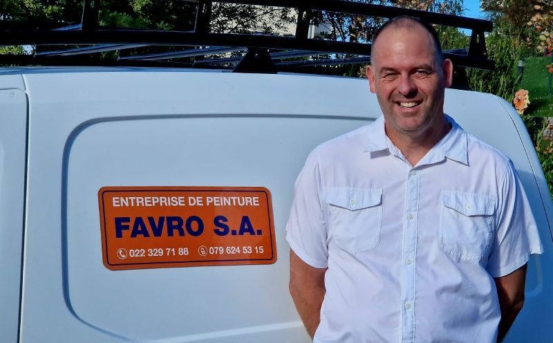 Un homme debout devant une camionnette blanche sur laquelle est écrit favre sa