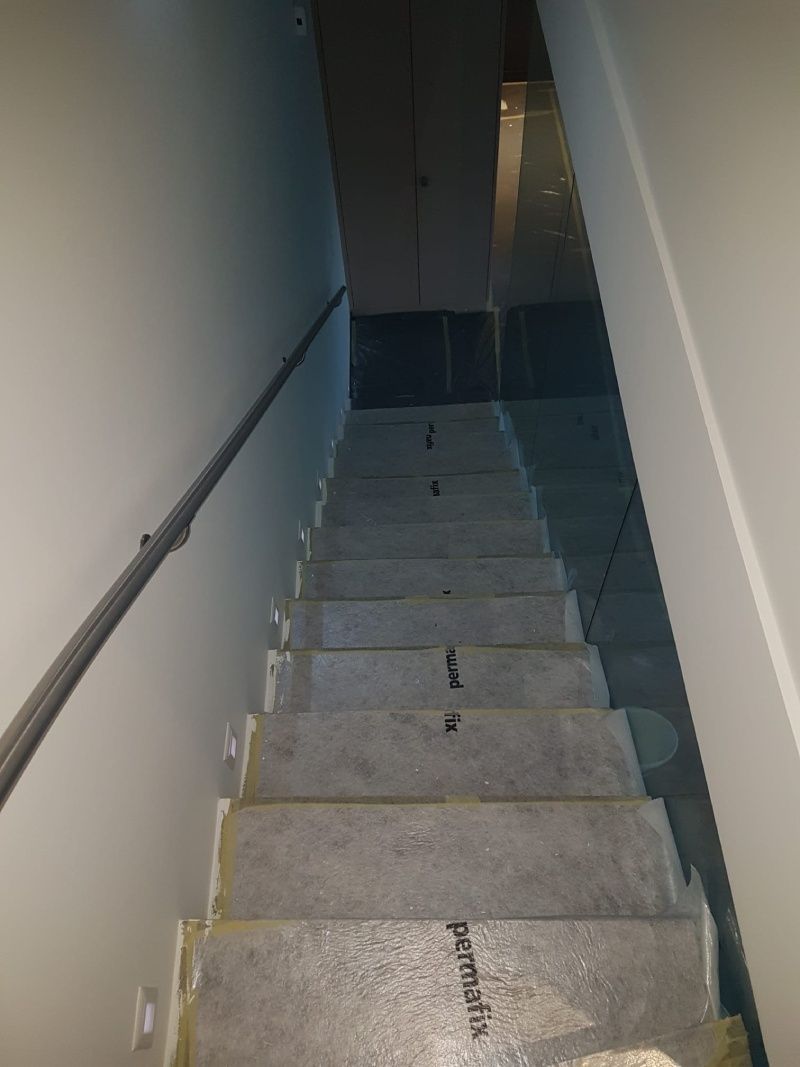 Un escalier menant à un sous-sol avec une rampe en métal.