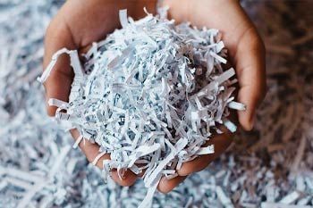 Una persona sostiene una pila de papel triturado en sus manos.